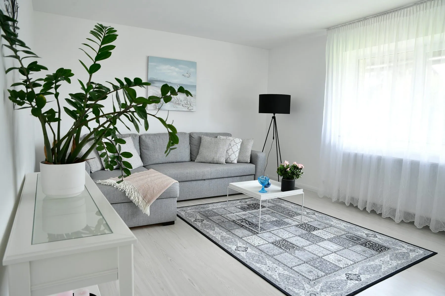 A typical Scandinavian-style living room in Espoo, featuring a bright white interior with a gray sofa and large cushions